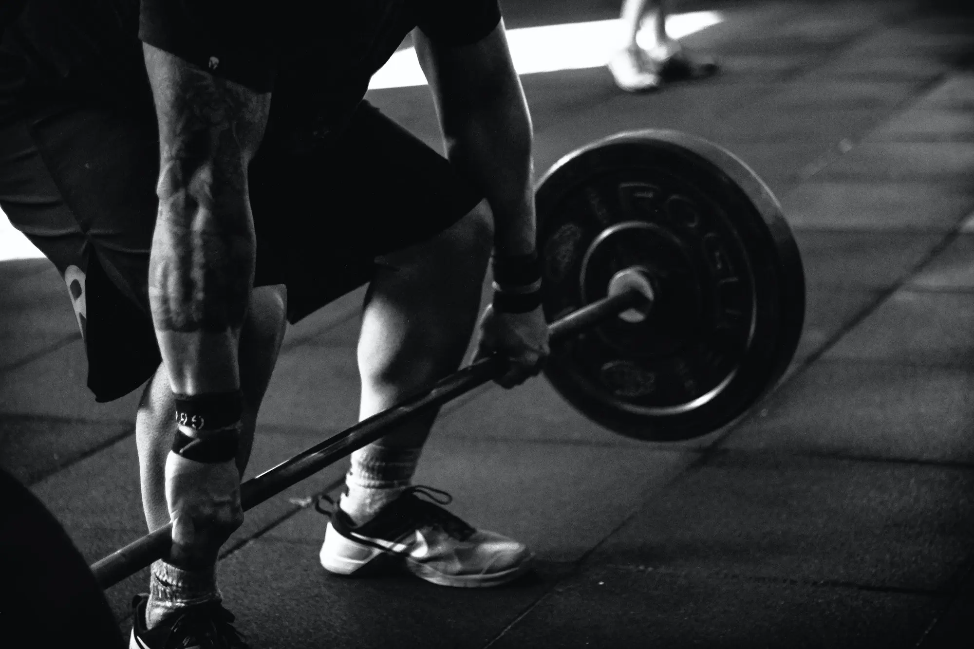 A black and white picture of a man that is about to lift a barbell. Used for a blog post